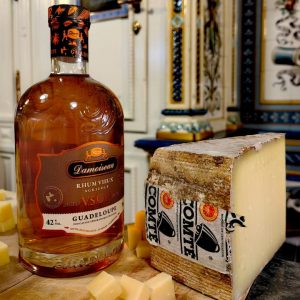 Abbildung eines Stück Comté Käse mit einer Flasche Rum aus Goadeloupe